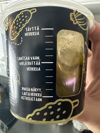 Kurkkusalaatti purkki jossa on kurkistusaukko ja kolme merkintää: ylimpänä täyttä herkkua, toisena santsaa vaan vielä riittää herkkua ja viimeisenä pohja näkyy, laita herkku ostoslistaan